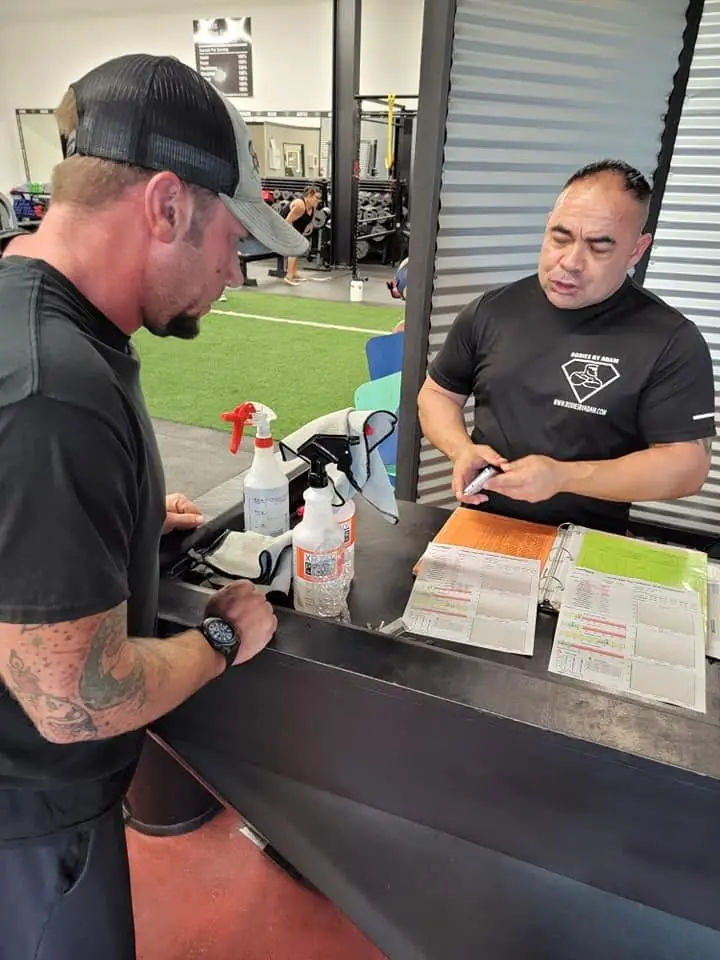 A coach reviewing a client’s assessment paperwork at the front desk