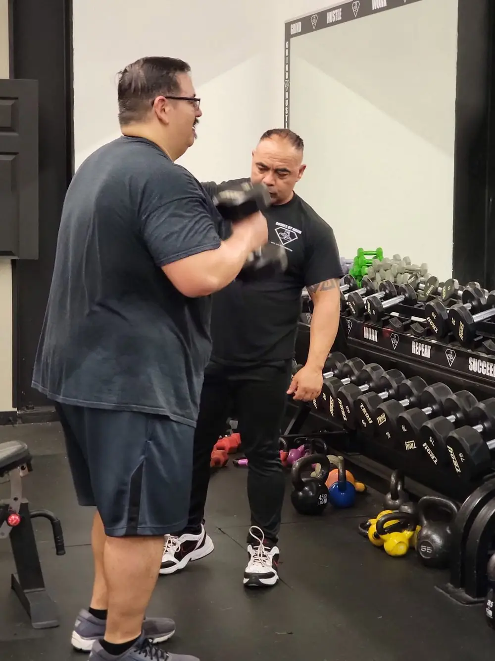 Coach working with a client on the dumbbell floor